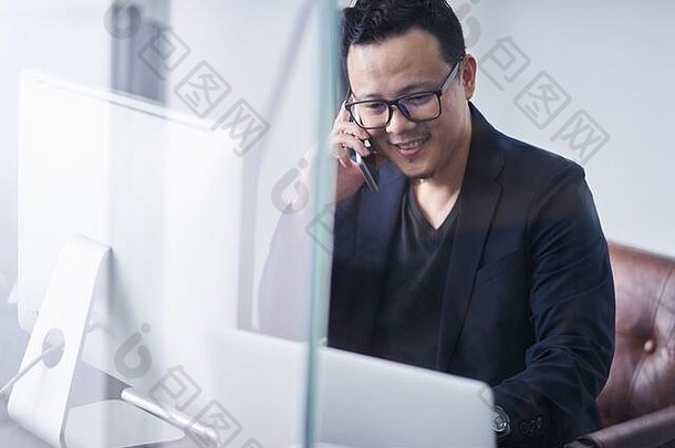 年轻的亚洲商人手机电脑工作