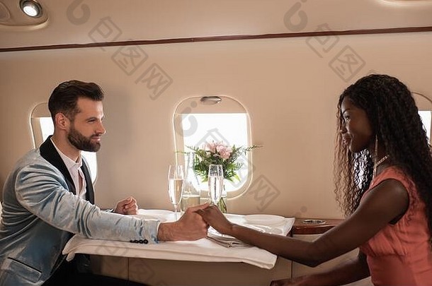 快乐优雅的跨种族夫妇持有手服务表格私人飞机