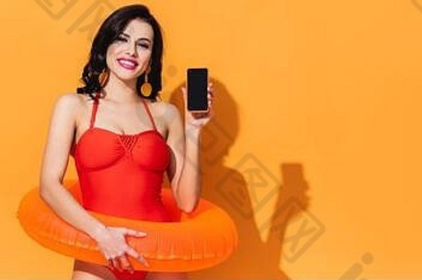全景概念快乐女人泳衣充气环持有智能<strong>手机</strong>空白屏幕橙色
