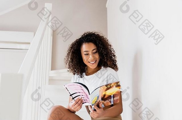 快乐非洲美国女人坐着楼梯杂志