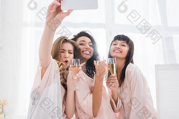 情感多民族女朋友眼镜香槟采取自拍智能手机睡衣聚会，派对