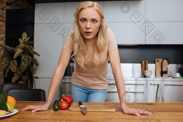 愤怒的年轻的女人相机站新鲜的蔬菜厨房