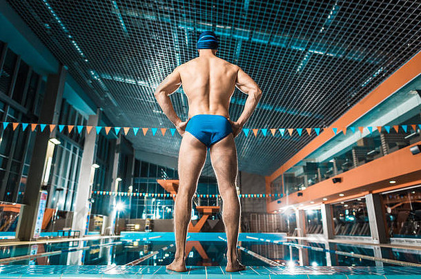 回来视图肌肉发达的运动员游泳帽护目镜站游泳池
