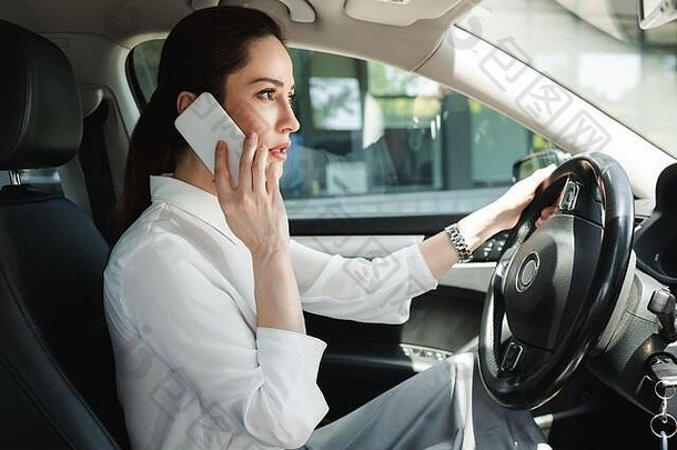 一边视图美丽的女商人会说话的智能手机开车车