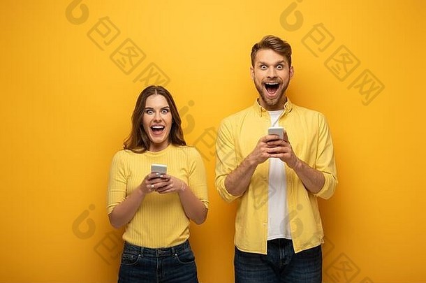 兴奋夫妇相机智能手机黄色的背景