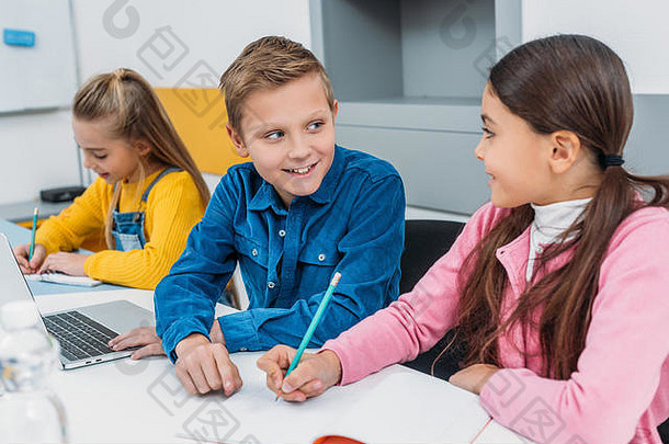 微笑孩子们坐着桌子上现代教室