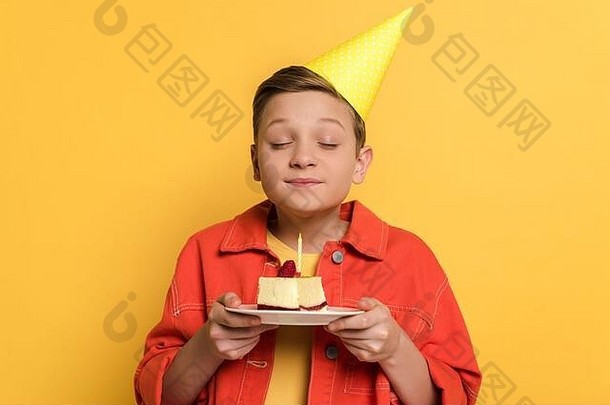 微笑孩子关闭眼睛使持有板生日蛋糕黄色的背景