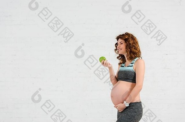 一边视图微笑怀孕了女人持有苹果白色背景