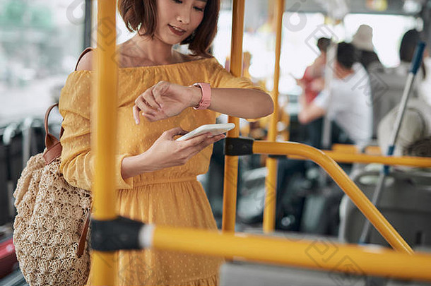 美丽的亚洲女人站公共汽车检查时间看