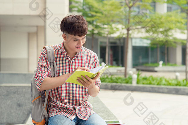 年轻的亚洲男人。背包阅读书