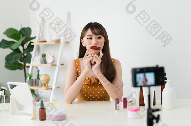 漂亮的年轻的女人坐着前面相机测试化妆品