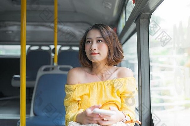 年轻的美丽的女人持有移动电话坐着公共汽车