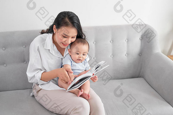妈妈抱着婴儿在沙发上教他看书识字