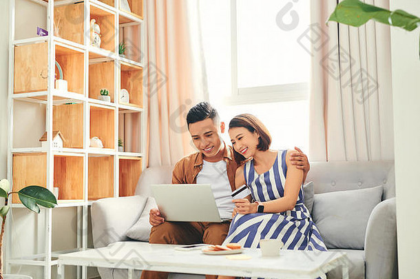 年轻的亚洲夫妇买家购买行信贷卡移动PC首页