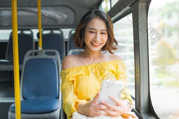 年轻的亚洲女人细胞电话公共运输公共汽车