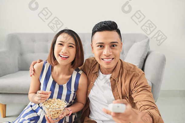 拍摄cheeful年轻的亚洲夫妇看电视首页