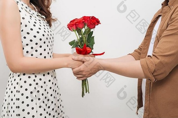 美丽的年轻的女人拥抱的男朋友持有不错的花束红色的玫瑰