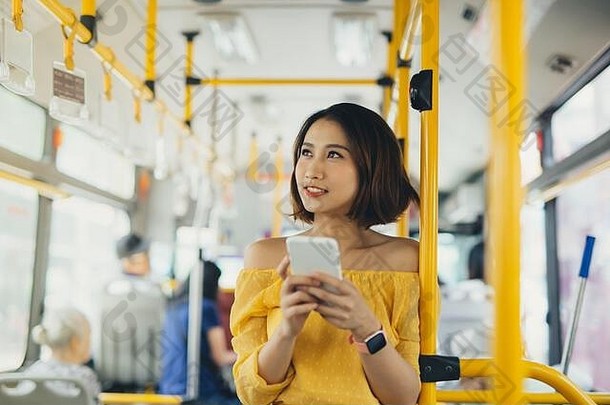 年轻的亚洲有吸引力的女人站公共汽车电话