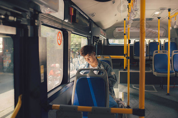 年轻的男人。坐着城市公共汽车阅读书