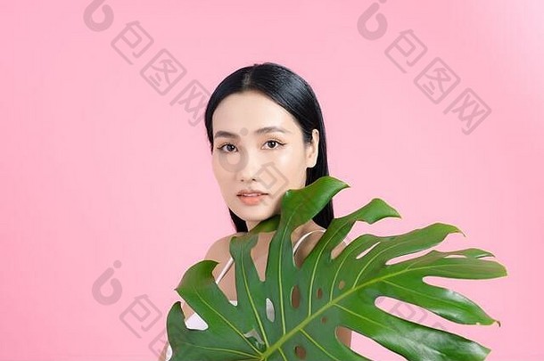 肖像年轻的美丽的亚洲女人持有热带叶粉红色的背景自然美概念