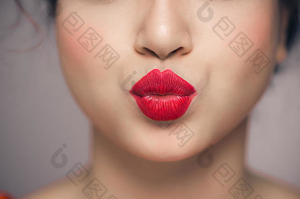 女人的嘴唇吹吻明亮的红色的口红