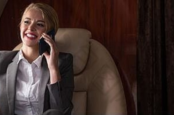 美丽的女商人会说话的智能手机飞机业务旅行