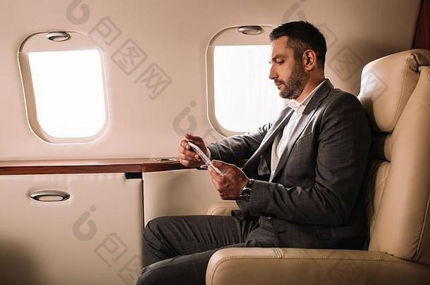 一边视图英俊的商人西装智能手机私人飞机