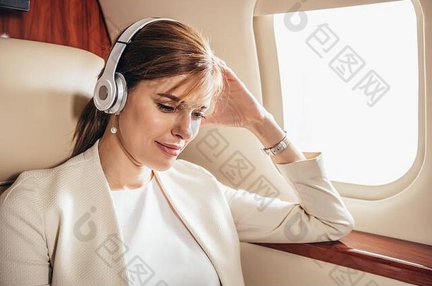 有吸引力的女商人西装听音乐耳机私人飞机