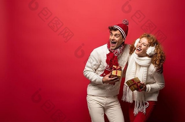 美丽的快乐夫妇冬天装持有圣诞节礼物孤立的红色的