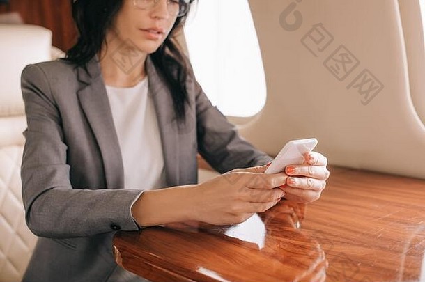 裁剪视图女商人持有智能手机私人飞机