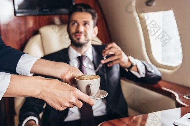 裁剪视图飞行之前给杯咖啡英俊的商人西装私人飞机