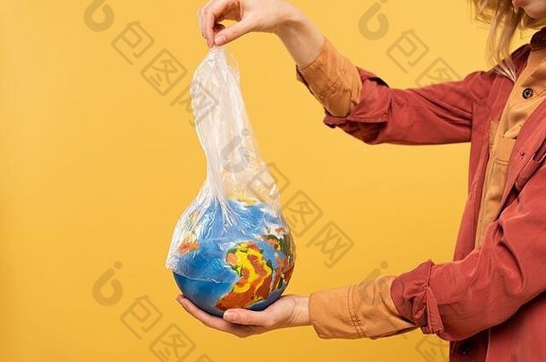 裁剪视图女人持有全球塑料包孤立的黄色的全球气候变暖概念