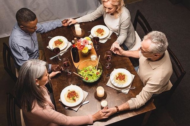 开销视图多元文化的朋友持有手祈祷晚餐