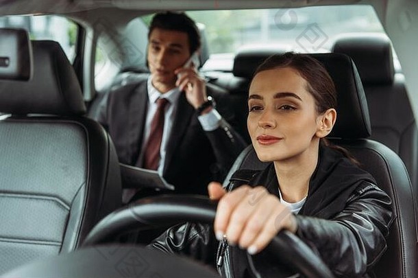女人出租车司机持有操舵轮商人会说话的智能手机