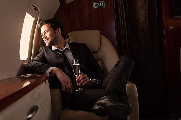 英俊的男人。持有玻璃香槟飞机