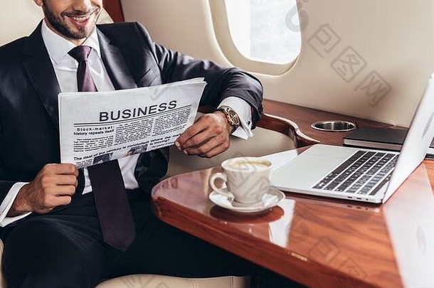 裁剪视图微笑商人西装阅读业务报纸私人飞机