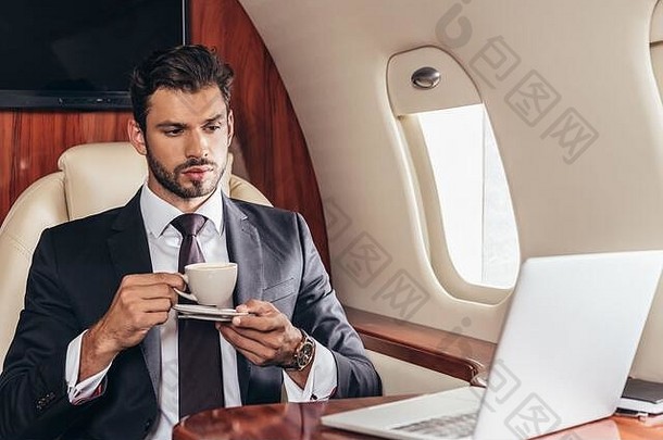 英俊的商人西装持有杯咖啡私人飞机
