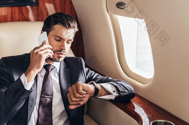 英俊的商人西装会说话的智能手机手表私人飞机