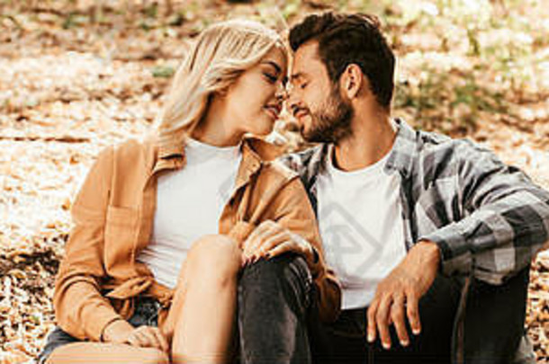 全景拍摄快乐年轻的夫妇坐着脸脸秋天叶子公园