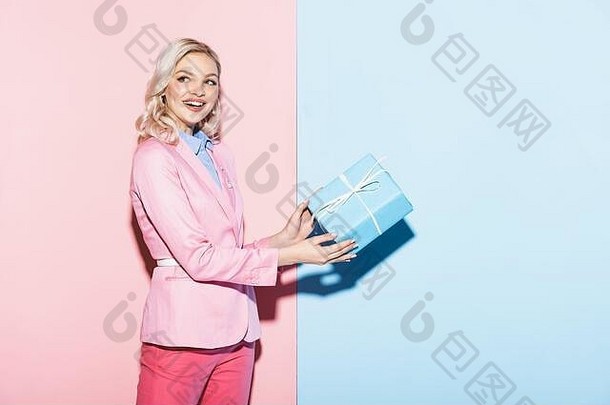 微笑女人持有礼物盒子粉红色的蓝色的背景
