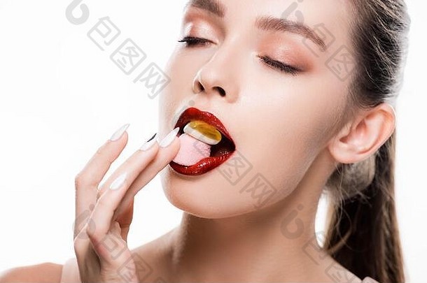 美丽的年轻的女人红色的嘴唇化妆吃糖果孤立的白色