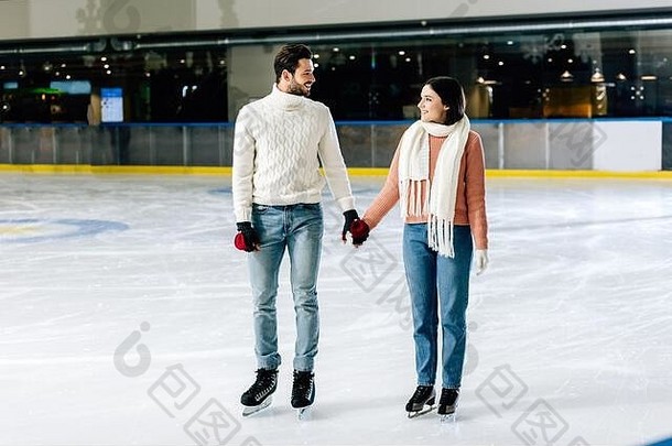 美丽的快乐夫妇持有手滑冰溜冰场