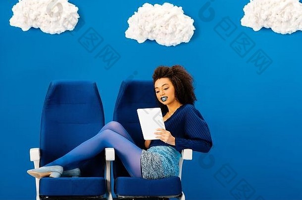 微笑非洲美国坐着座位数字平板电脑蓝色的背景云