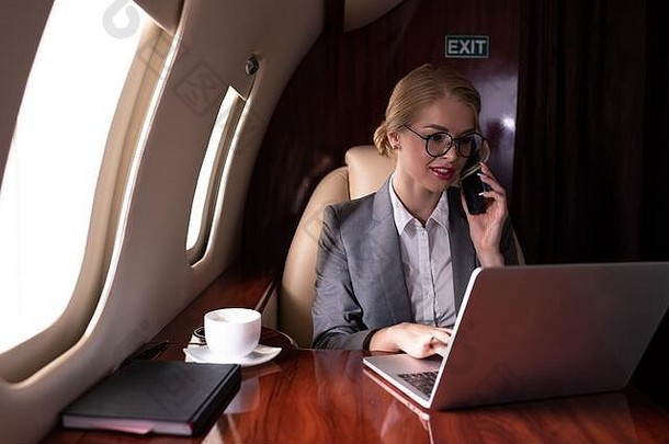 女商人会说话的智能手机工作移动PC飞机业务旅行