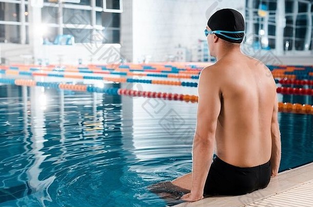 肌肉发达的运动员游泳帽坐着游泳池