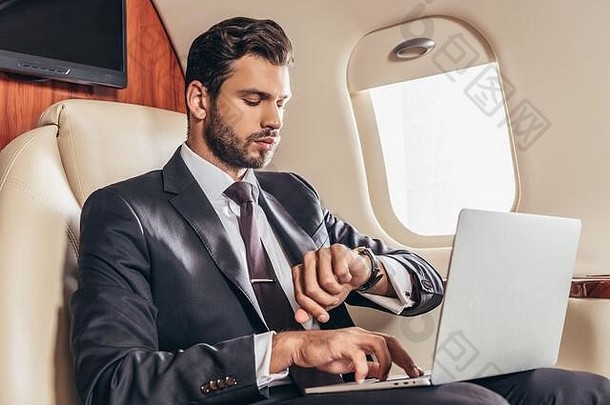 英俊的商人西装移动PC手表私人飞机