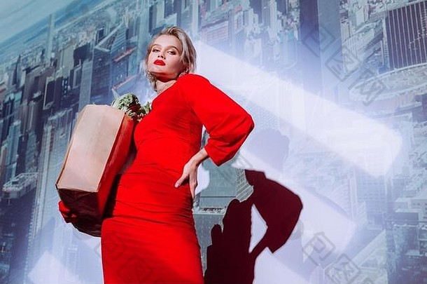 低角视图有吸引力的时尚的女人红色的衣服持有纸袋食物城市背景