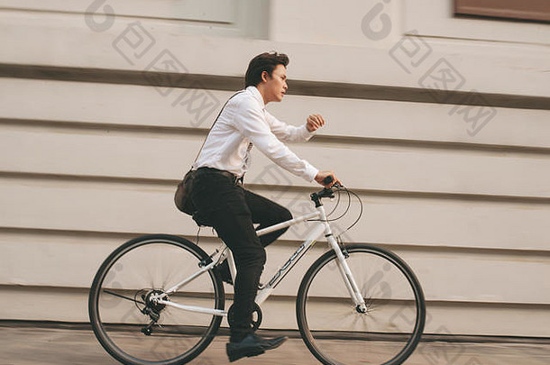 快点亚洲商人骑自行车冲小时年轻的男人。晚些时候火车工作会议办公室生活业务竞争