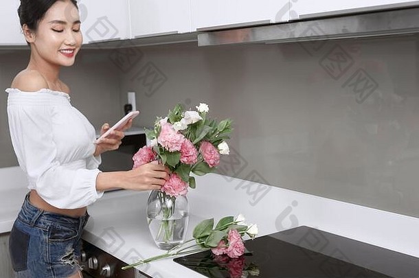 美丽的亚洲女人采取花厨房