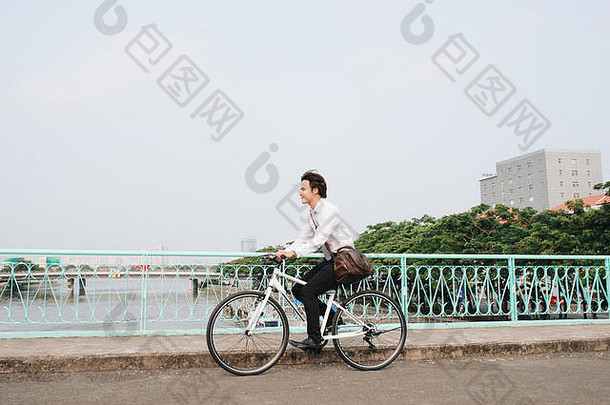 自行车一边视图年轻的商人向前骑自行车